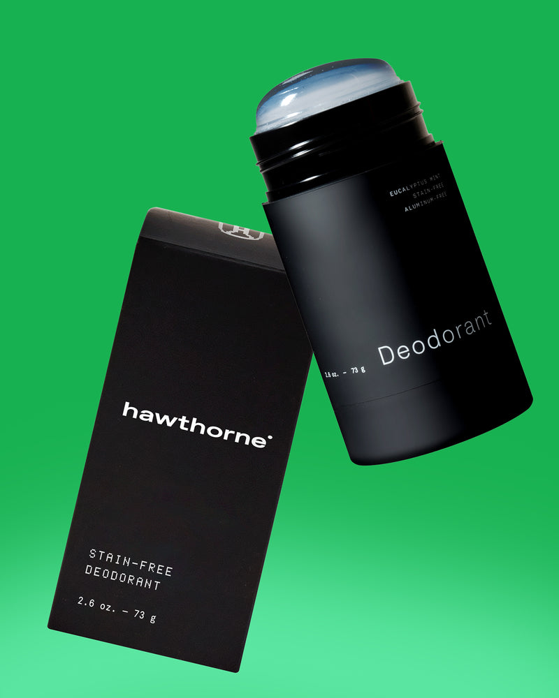 A black stick of Hawthorne deodorant with its matching black box, both labeled stain-free deodorant, against a green background.