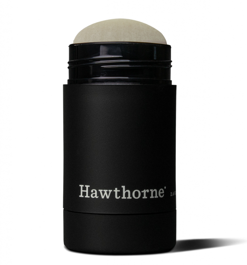A black cylindrical hawthorne Natural Deodorant container with the cap off, revealing the deodorant inside made with eucalyptus and sage oil.