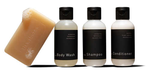 The hawthorne Travel Shower Set, featuring a Natural Bar Soap, Exfoliating Body Wash, Hydrating Shampoo, and conditioner, is arranged neatly in a row.